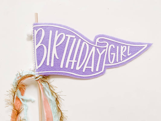 Purple 'Birthday Girl' banner with decorative ribbons on a white background